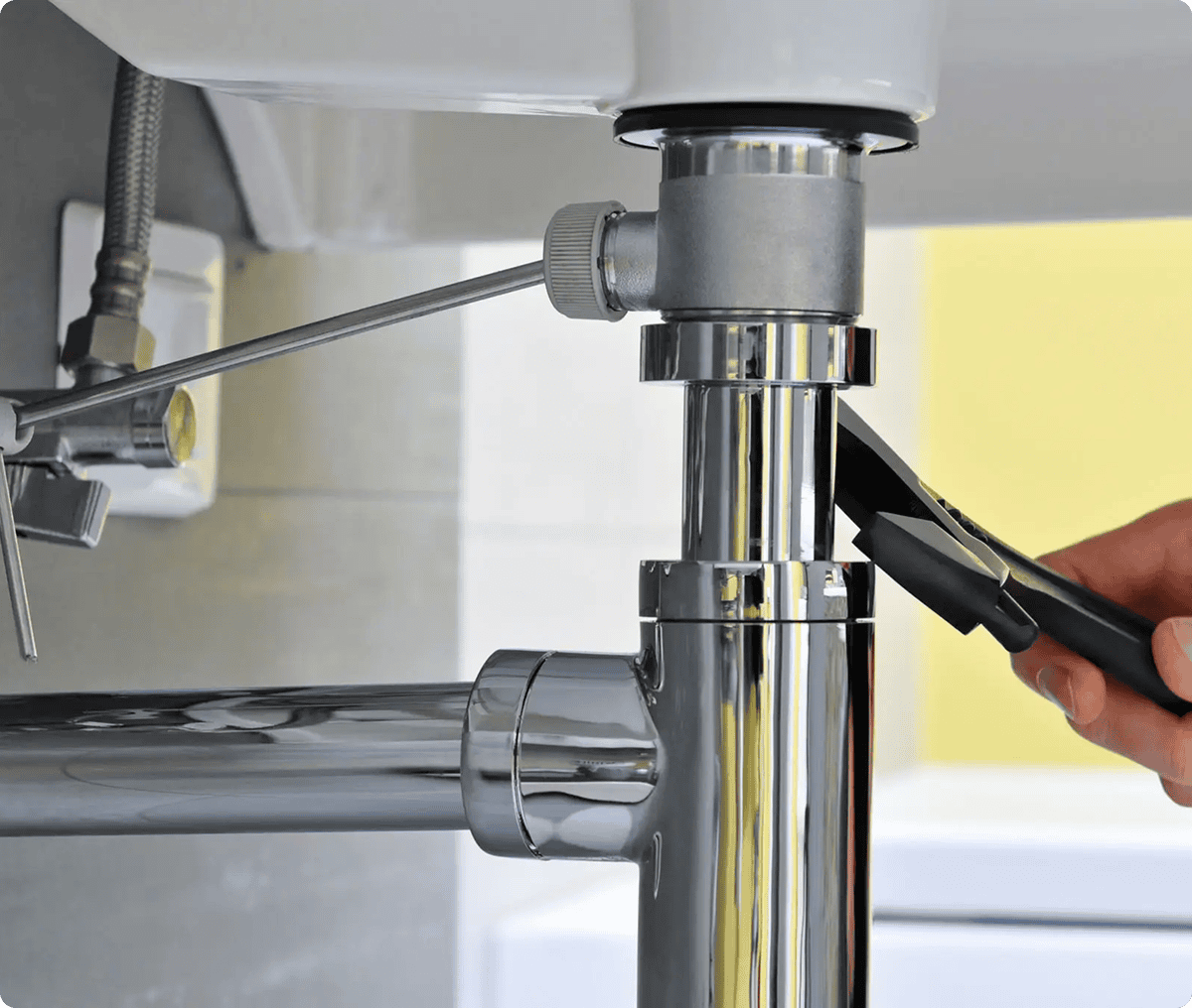 Adjusting sink plumbing with pipe wrench