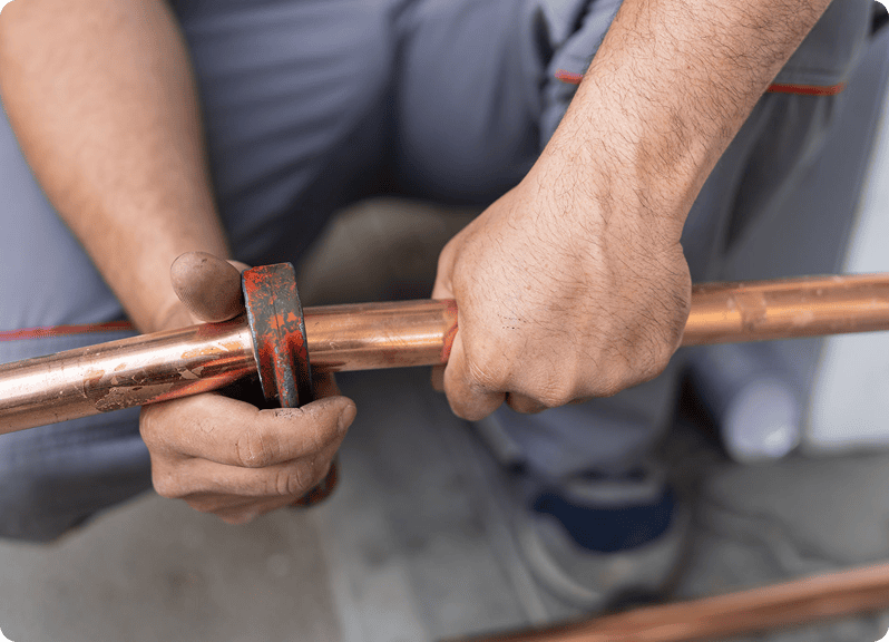 Hands working on copper plumbing pipe