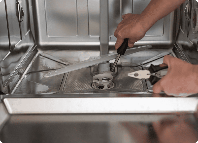 Hands servicing dishwasher interior