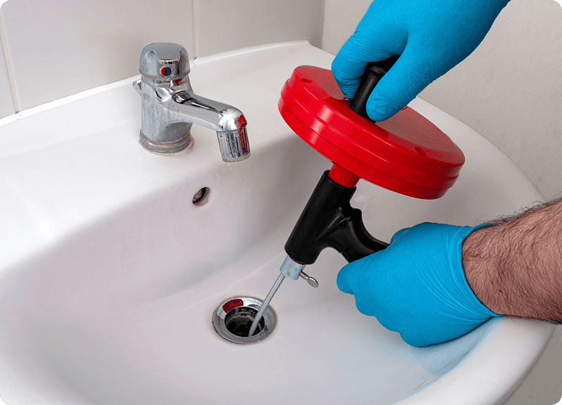Plumber using tool to unclog sink drain